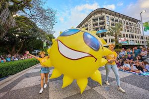Performers carry a giant inflatable sun in the Cairns Festival Grand Parade on the Esplanade