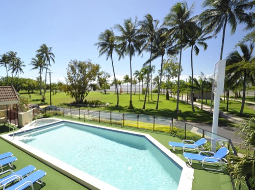 Coral Towers pool and sun lounges facing the palm-lined Cairns Esplanade
